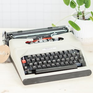 Máquina de escribir portátil Gracia de Luxe con mantenimiento profesional y envío rápido a todo el mundo, con cinta de tinta azerty nueva.