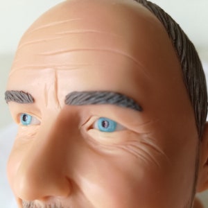 Attorney bobblehead close up. Man has blue eyes and grey hair.