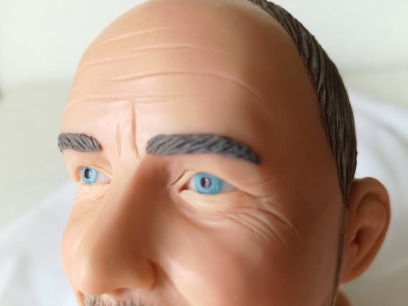 Attorney bobblehead close up. Man has blue eyes and grey hair.
