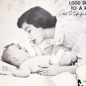 May include: A black and white advertisement for ScotTissue toilet paper. The ad features a mother and baby, with the text "1,000 sheets to a roll...and so soft for his tender skin."  The ad also states that "1,000 sheets - over 1/2 more than the 650 tissues you get from most other brands."  The ad also states that "3 rolls of ScotTissue equal 4 1/2 rolls of most other brands."