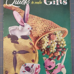 May include: A vintage craft book cover with a green background, showcasing crochet projects. It features a crochet bunny, cat, and a cornucopia overflowing with grapes and nuts. The title reads "Quick to make Gifts".