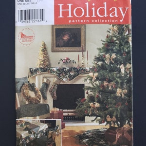 Puede incluir: Un patrón de costura Simplicity Holiday para una falda de árbol de Navidad, una bufanda para la repisa de la chimenea y un camino de mesa. El patrón presenta un diseño floral con acentos rojos, verdes y dorados. El número de patrón es 8396.