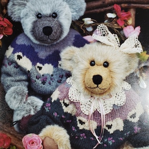 May include: Two plush teddy bears wearing knitted sweaters with floral and heart patterns. The bear on the left is gray with a blue and gray sweater. The bear on the right is brown with a pink and gray sweater and a white lace collar.