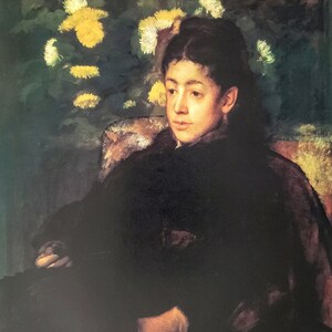 May include: A woman in a dark dress sits in a chair, looking to the side. She is surrounded by white and yellow flowers.
