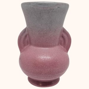 Puede incluir: Un jarrón de cerámica con un diseño bicolor que presenta un acabado gris moteado en el cuello ensanchado superior y un acabado rosa moteado en el cuerpo redondeado. El recipiente incluye dos asas laterales integradas y una base circular.