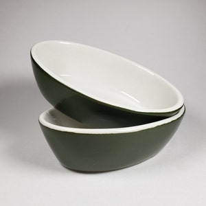 May include: Two green ceramic bowls with white interiors. The bowls are stacked on top of each other.