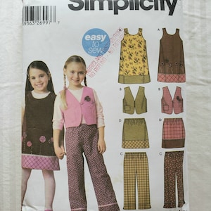 Op de afbeelding: Simplicity naaipatroon nummer 1489 voor meisjeskleding. Het patroon bevat instructies voor een jurk, een vest, een rok en een broek. Het patroon is gemakkelijk te naaien en bevat geen instructies voor terugbetaling of retour.