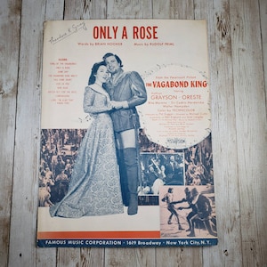 May include: Sheet music for the song "Only a Rose" from the musical "The Vagabond King". The sheet music features a photo of Kathryn Grayson and Oreste in a scene from the musical. The sheet music is published by Famous Music Corporation.