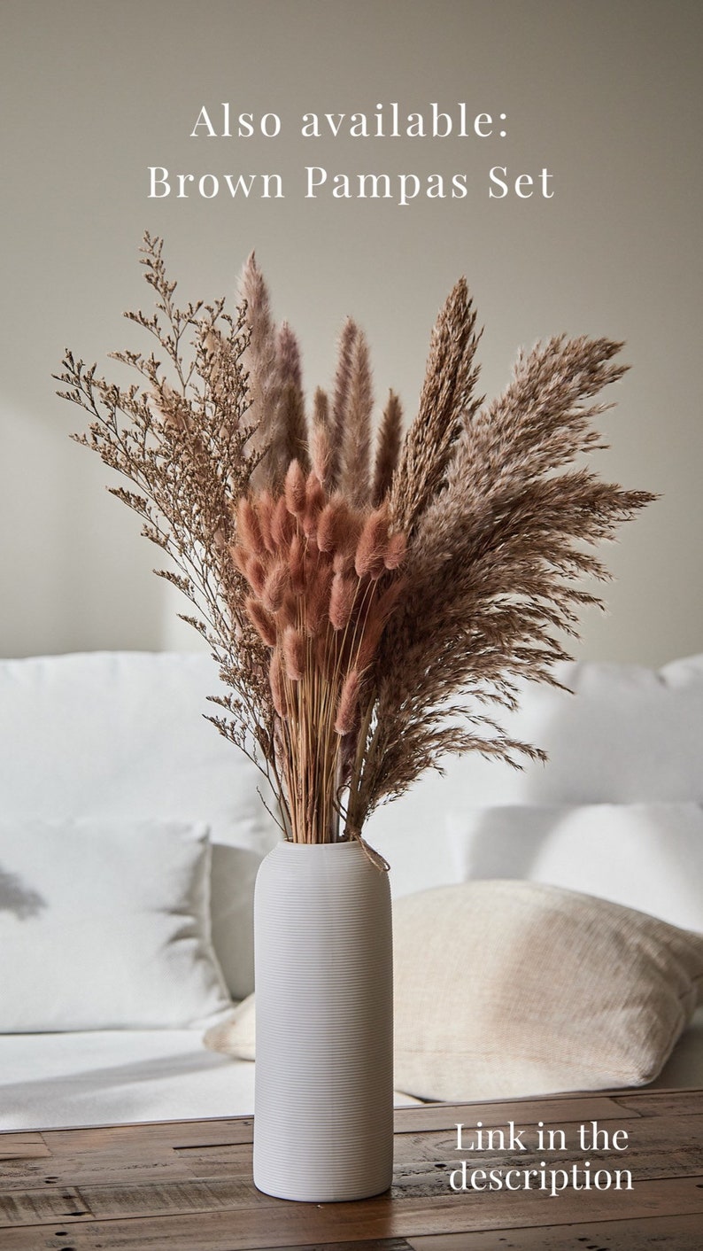 Op de afbeelding: Een witte keramische vaas gevuld met gedroogd pampasgras, konijnenstaarten en andere gedroogde grassen. De vaas staat op een houten tafel. Ook verkrijgbaar: Bruin Pampas-Set. Link in de beschrijving.