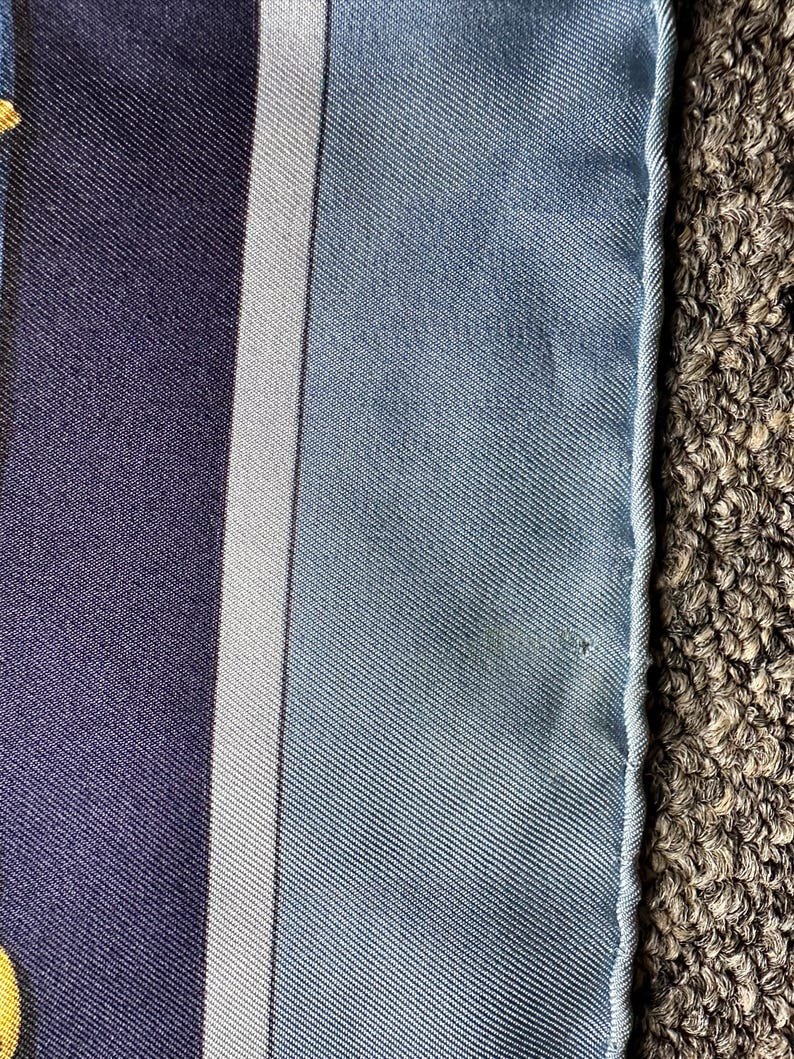 May include: A close-up of a blue and white striped fabric with a white border. The fabric has a subtle texture and a slight sheen.