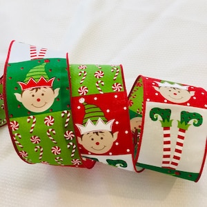 May include: Three rolls of Christmas ribbon featuring a festive elf design. The ribbon is red, green, and white with candy canes, polka dots, and elf faces.