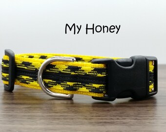Puede incluir: Un collar para perro de color amarillo y negro con una hebilla de plástico negra y un anillo en D plateado. El collar tiene el texto "My Honey" impreso en él.