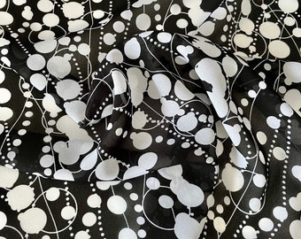 Printed polyester crepe, white strands of pearls on a black background