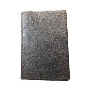 Peut inclure: Un livre rectangulaire gris foncé avec une couverture texturée semblable à du cuir. Le livre est fermé et présente un aspect légèrement usé, suggérant qu'il a été utilisé. Les bords sont arrondis.