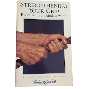 Puede incluir: Un libro titulado "Strengthening Your Grip" con el subtítulo "Essentials in an Aimless World". La portada muestra unas manos agarrando una cuerda. También se ve el nombre del autor, Charles R. Swindoll.