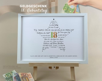 May include: A white framed print featuring a star-shaped arrangement of German text and the number 18, with the name Leon, a date, and inspirational phrases. The print is displayed on a wooden easel with euro banknotes visible nearby.