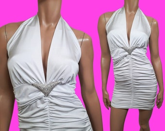 May include: White halter top with a ruched bodice and a silver rhinestone embellishment. The top is sleeveless and has a deep V-neckline.