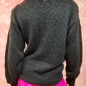May include: A black knitted sweater with long sleeves. The sweater is made of a soft, textured material.