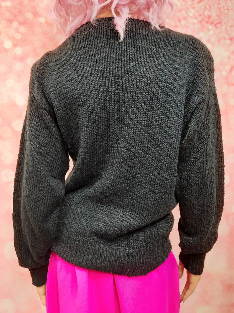May include: A black knitted sweater with long sleeves. The sweater is made of a soft, textured material.