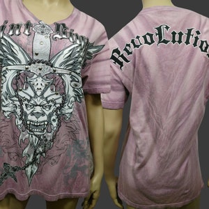May include: A pink tie-dye t-shirt with a graphic print of a winged sword, a skull, and the text "Mint Sin" on the front. The back of the shirt has the text "Revolution" printed in black.