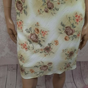 May include: A white dress with a floral print featuring pink, orange, and brown flowers. The dress has a textured fabric and a slightly gathered skirt.
