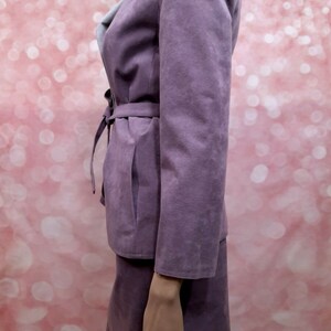 May include: A purple suede skirt suit with a long-sleeved jacket and a matching skirt. The jacket has a tie belt and a collar.