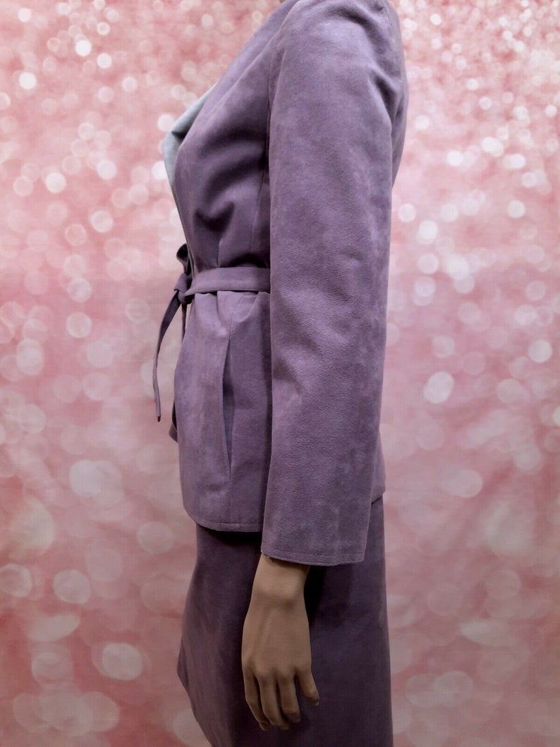 May include: A purple suede skirt suit with a long-sleeved jacket and a matching skirt. The jacket has a tie belt and a collar.