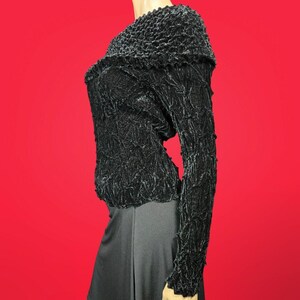 May include: Black, long-sleeved, textured sweater with a slightly off-the-shoulder neckline.