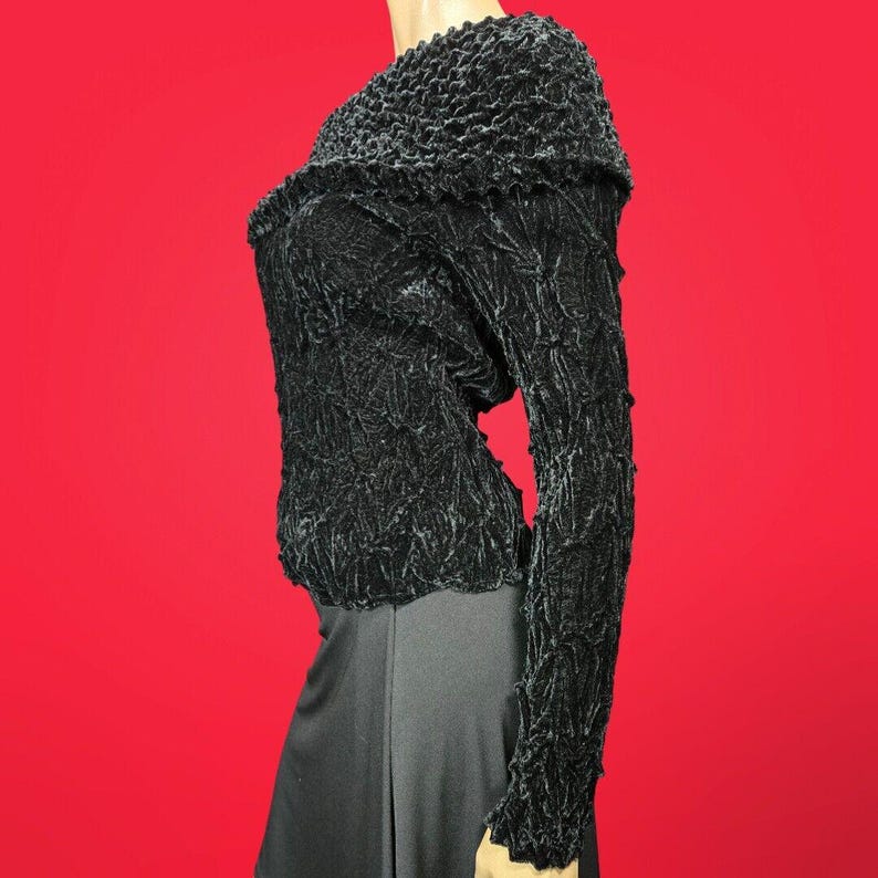 May include: Black, long-sleeved, textured sweater with a slightly off-the-shoulder neckline.