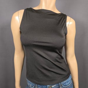 May include: A black sleeveless top with a boat neck design. The top is made of a smooth, solid fabric and has a fitted silhouette. The garment is displayed on a mannequin.