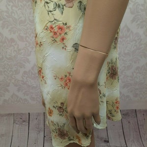 May include: A light yellow floral print dress with a ruffled hem. The dress is made of a soft, flowing fabric.