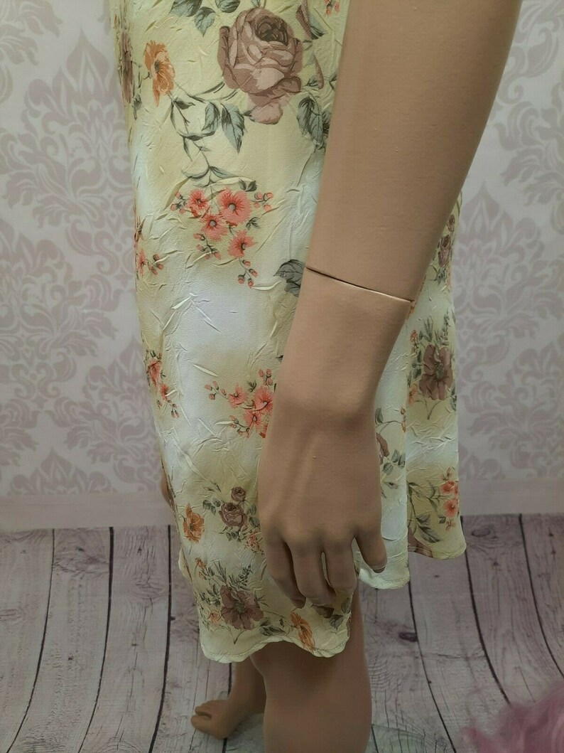 May include: A light yellow floral print dress with a ruffled hem. The dress is made of a soft, flowing fabric.