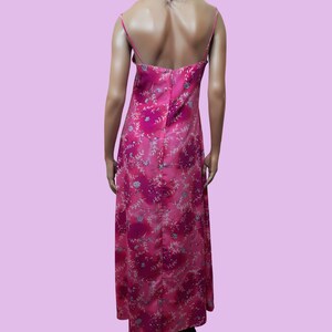 May include: A pink maxi dress with a floral print. The dress has a spaghetti strap design and a back zipper closure.