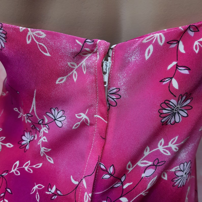 May include: A pink dress with a white floral print and a zipper in the back.