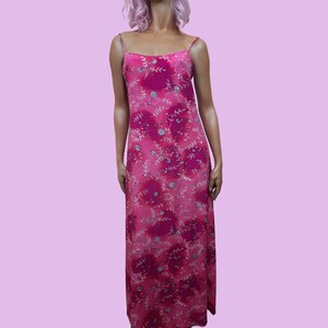 May include: A pink maxi dress with a floral print. The dress has thin straps and a flowy skirt.