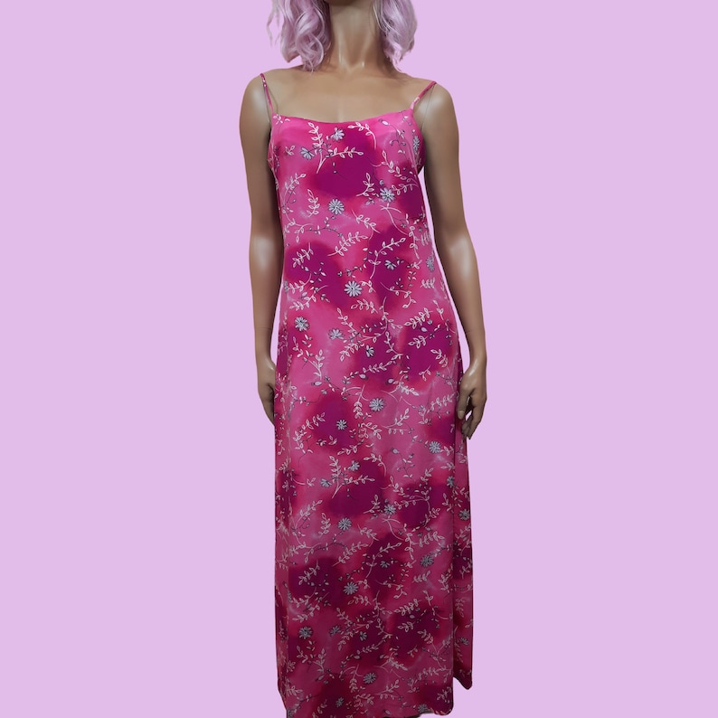 May include: A pink maxi dress with a floral print. The dress has thin straps and a flowy skirt.