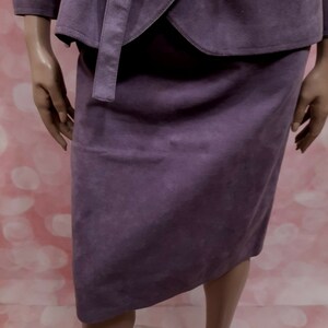 May include: A purple suede skirt suit with a wrap jacket and a straight skirt.