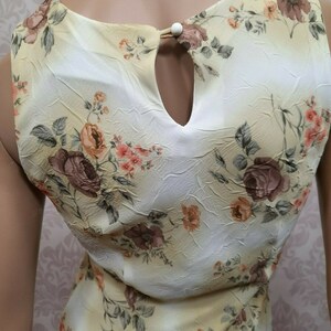 May include: A sleeveless dress with a floral print in shades of brown, pink, and yellow. The dress has a keyhole opening at the back of the neckline.