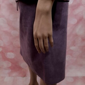 May include: A purple suede skirt with a straight silhouette and a slightly flared hem.