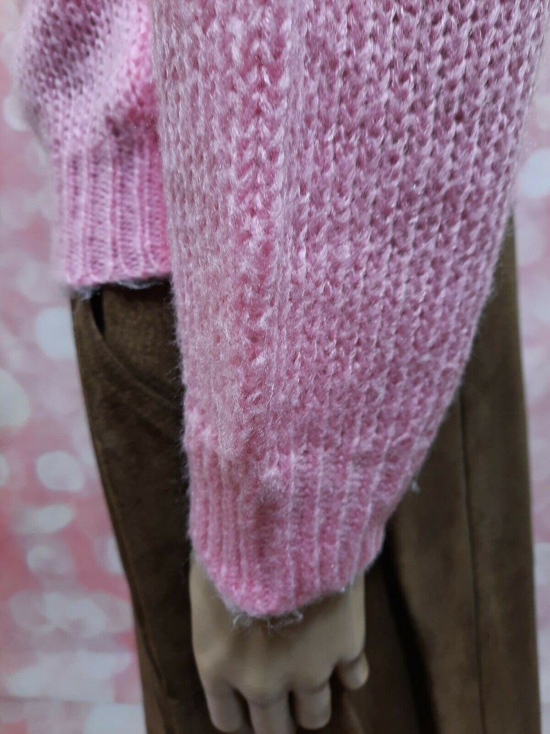 May include: A pink fuzzy knit sweater with a ribbed texture. The sweater is shown on a mannequin wearing brown pants.