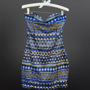 May include: A strapless sequined mini dress with a geometric pattern in shades of blue, gold, and black.