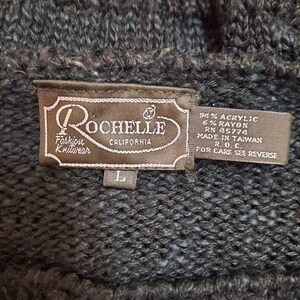 May include: A brown tag with the text "Rochelle Fashion Knitwear California" and size label "L". The tag also includes the fabric content: 94% Acrylic, 6% Rayon, RN 45774, Made in Taiwan, R.O.C., For Care See Reverse.