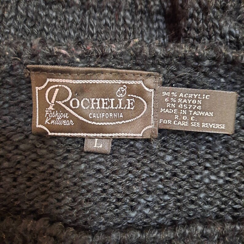 May include: A brown tag with the text "Rochelle Fashion Knitwear California" and size label "L". The tag also includes the fabric content: 94% Acrylic, 6% Rayon, RN 45774, Made in Taiwan, R.O.C., For Care See Reverse.