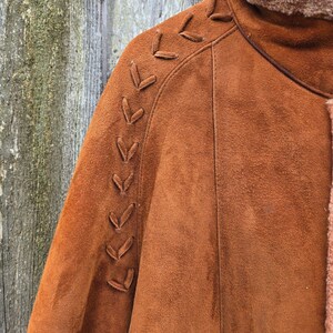 May include: A brown suede jacket with a braided detail on the shoulder. The jacket has a shearling lining.