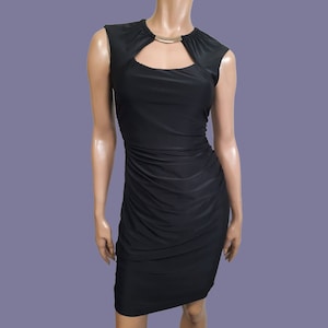 May include: A black sleeveless dress with a keyhole neckline and a gold accent. The dress is fitted and has a ruched design.