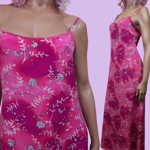 May include: A pink maxi dress with a floral print. The dress has thin straps and a loose fit.