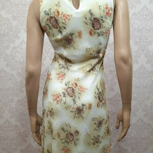 May include: A sleeveless yellow dress with a floral print featuring brown and orange roses. The dress has a keyhole opening at the back of the neckline.