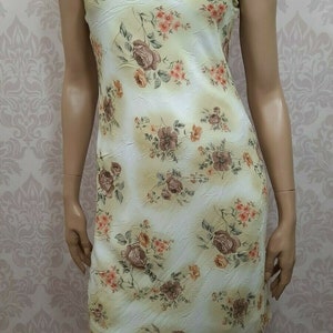 May include: A sleeveless dress with a floral print in shades of brown, pink, and yellow on a white background. The dress has a scoop neck and a fitted silhouette.
