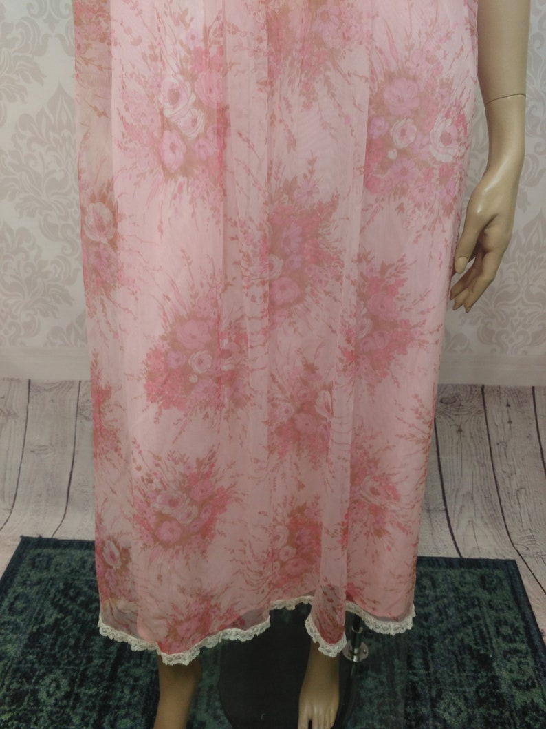 Pode incluir: Camisa de noite vintage rosa claro com um padr&atilde;o floral em tons de rosa e castanho. A camisa de noite apresenta uma delicada renda na bainha. O tecido parece leve e fluido, sugerindo um ajuste confort&aacute;vel.