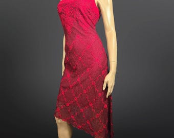 May include: A strapless, knee-length red dress with intricate floral lace detailing. The dress features a fitted bodice and an asymmetrical hemline. The fabric appears to be a deep red, with a darker shade in the lace pattern.